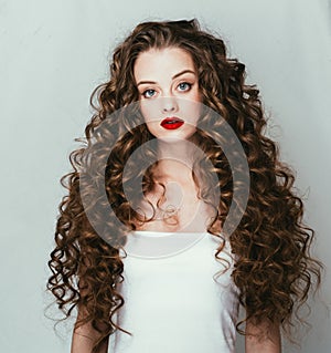 Curly hair woman portrait long hair with perfect make up red lips.