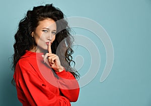 Curly hair woman showing hush quite tsss sign with red lips and sweater photo