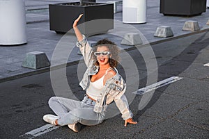 Curly hair woman in sunglasses and jacket walking in the city