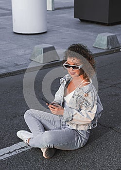 Curly hair woman in sunglasses and jacket walking in the city