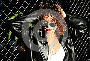 Curly hair woman in sunglasses and leather jacket