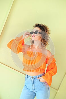 Curly hair woman in sunglasses posing on dark background