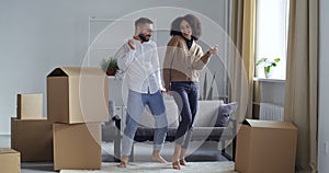 Curly-haired African American girl in black pants and brown sweater and Caucasian man in jeans and white shirt dancing