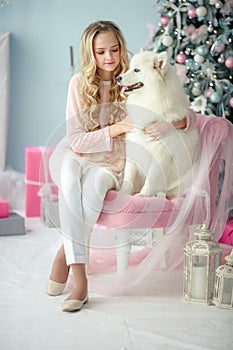 A curly-haired blonde with a best and faithful friend a purebred dog poses in a New Year& x27;s decorated studio