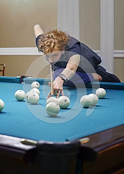 Curly-haired girl plays Billiards, performs a difficult blow. Curly-haired girl plays Billiards, performs a difficult blow.