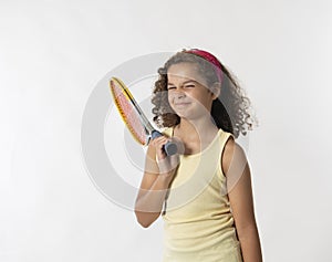 Curly haired girl wrinkling nose while holding tennis racket