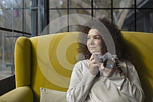 Curly haired photographer woman holding her camera in a cafe and shooting