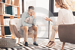 Curly-haired psychoanalyst speaking to her client