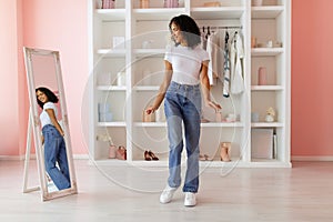 Curly-haired woman admires fit of jeans