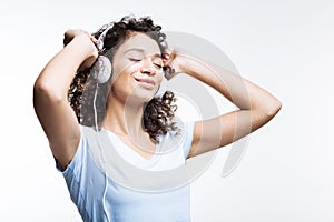 Curly-haired woman listening to music in headphones