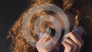 Curly haired young woman hides her face in a fur collar