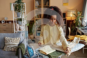 Curly Haired Young Woman Ironing Clothes on Laundry Day