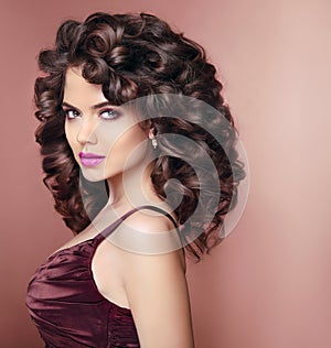 Curly hairstyle. Beautiful smiling woman with makeup and healthy