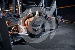 Curly-headed sportswoman doing the incline leg press