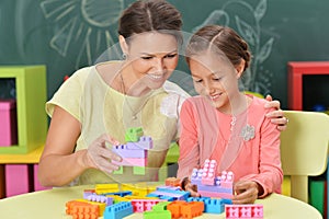 Curly little girl and her mother playing with colorful plastic b