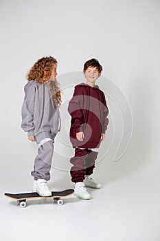 Curly long-haired girl and boy in tracksuits on a white background