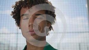 Curly model winking camera at stadium background portrait. Smiling man posing