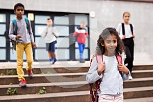 Curly mulatto tween girl walking to school campus after lessons