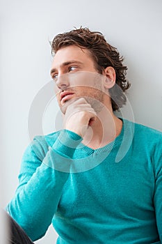 Curly pensive young man thinking and looking at the window