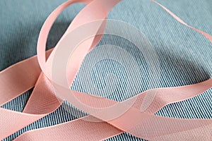 Curly pink ribbon on blue fabric background
