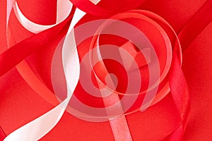 Curly satin ribbons and origami heart on red paper background, close-up. Valentine`s day card, poster