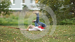 Curly schoolboy runs through the park with his dog. The boy stumbles and unexpectedly falls. Accident