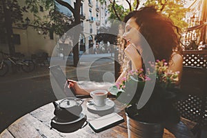 Curly smiling beautiful girl using digital tablet in cafe