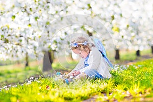 Curly toddler girl in fairy costume in fruit garden