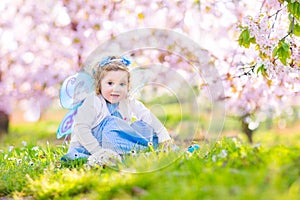 Curly toddler girl in fairy costume in fruit garden