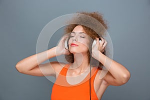 Curly woman with eyes closed in headphones listening to music