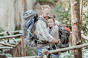 Curly woman feeling relieved hugging her man after hiking with backpacks