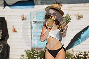 Curly woman in hat drinking cocktail and having fun near pool. Vacation concept