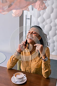 Curly woman laughing speaking on the phone with friend