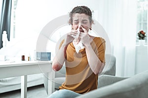 Curly woman with reddening on elbow using nose spray