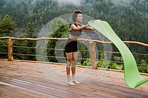 Curly woman unrolling fitness mat for yoga practice