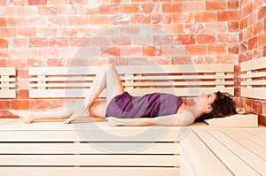 Curly young female stretched out on wooden bench