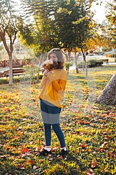 Curly young girl in yellow sweater on grass with autumn bouquet of dry leaves and flowers