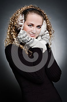 Curly young woman in furs earphone and mitten