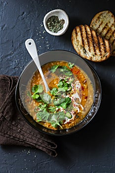 Curried red lentil tomato and coconut soup - delicious vegetarian food on dark background