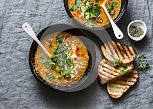 Curried red lentil tomato and coconut soup - delicious vegetarian food on grey background, top view. Flat lay