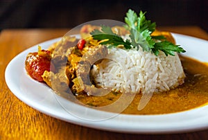 Curry chicken bright juicy with white rice on plate over wooden background. side view.