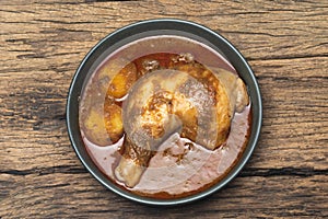 Curry chicken with coconut in bowl on wood background