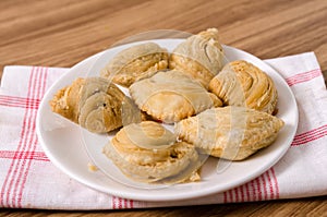 Curry puff snacks on white dish with wooden background..