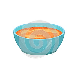 Curry or spicy orange sauce in bright blue ceramic dip bowl. Gravy for various dishes. Cooking ingredient. Culinary
