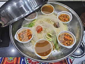 Curry with vegetables and meat in a pan on a table in a restaurant