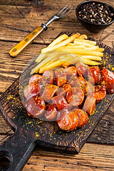 Curry wurst Sausages with French fries on a wooden board. wooden background. Top view