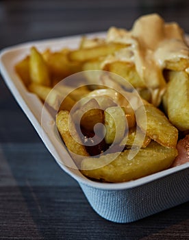 currywurst with fries into a cup. traditional german food to go with dip at corona times
