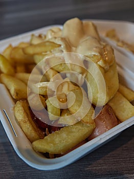 currywurst with fries into a cup. traditional german food to go with dip at corona times photo