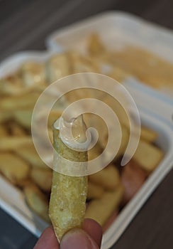 currywurst with fries into a cup. traditional german food to go with dip at corona times, focus on frie in hand photo