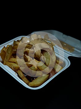 currywurst with fries into a cup. traditional german food to go with dip at corona times, negative space photo